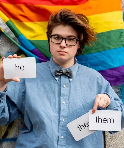 non-binary-person-with-glasses-holding-pronouns-cards