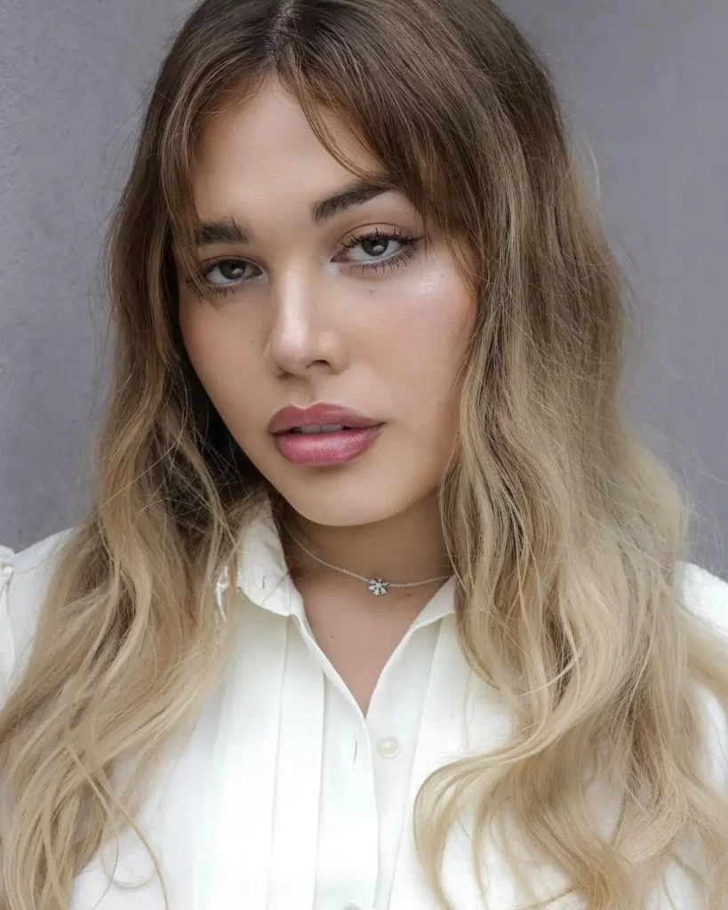 AJ Clementine with blonde hair in white blouse.