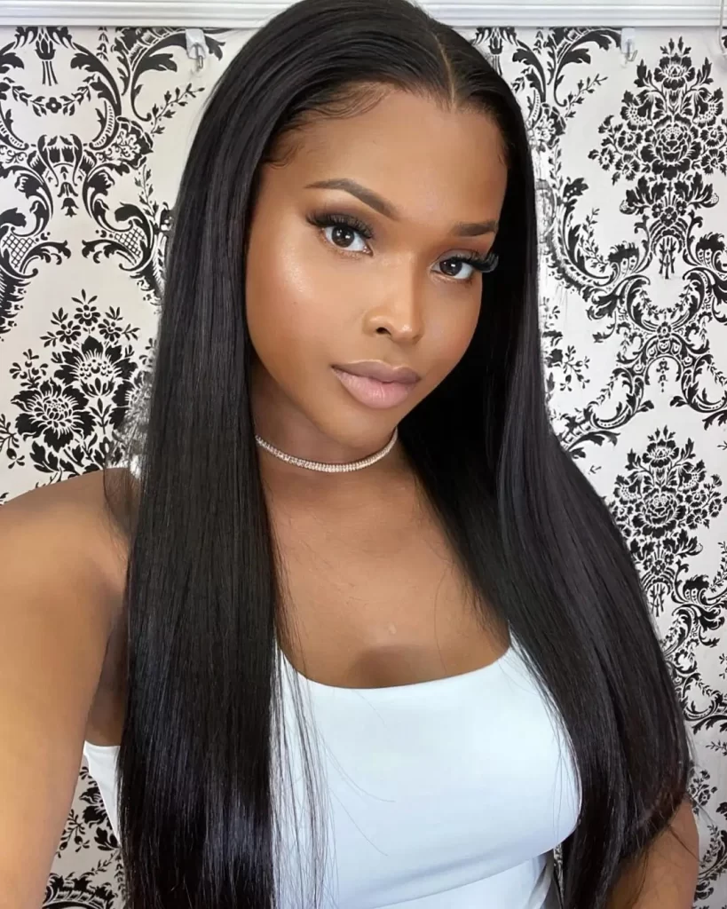 Amiyah Scott with straight hair and makeup against patterned backdrop.