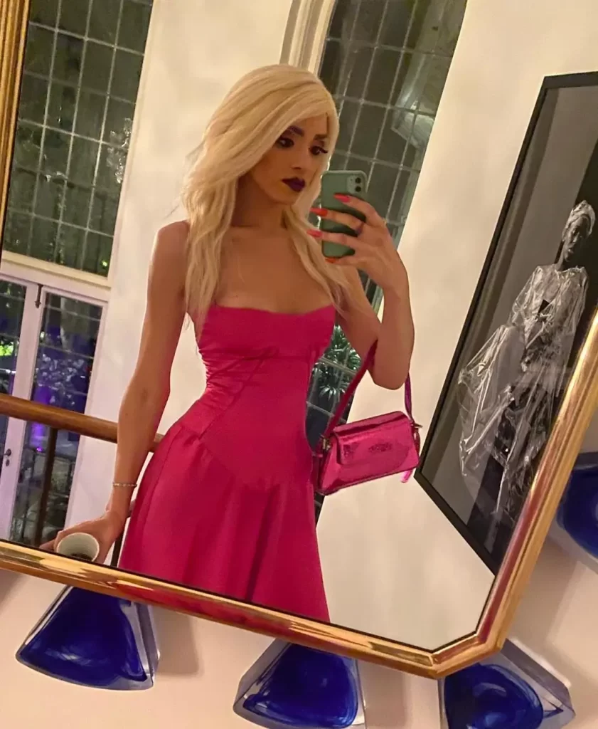 Arisce Wanzer in pink dress taking mirror selfie.