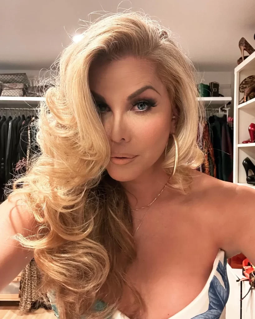 Candis Cayne with voluminous blonde hair in a closet.