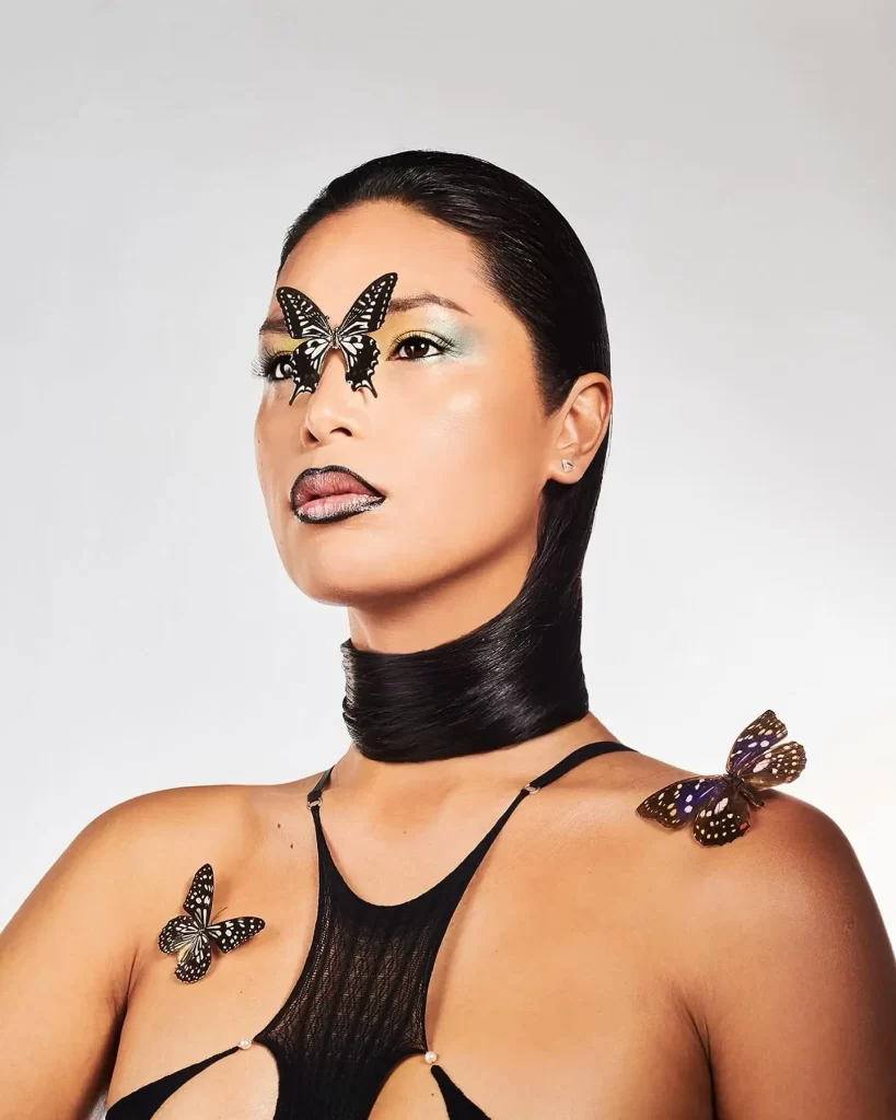 Geena Rocero with butterflies on face and shoulder.