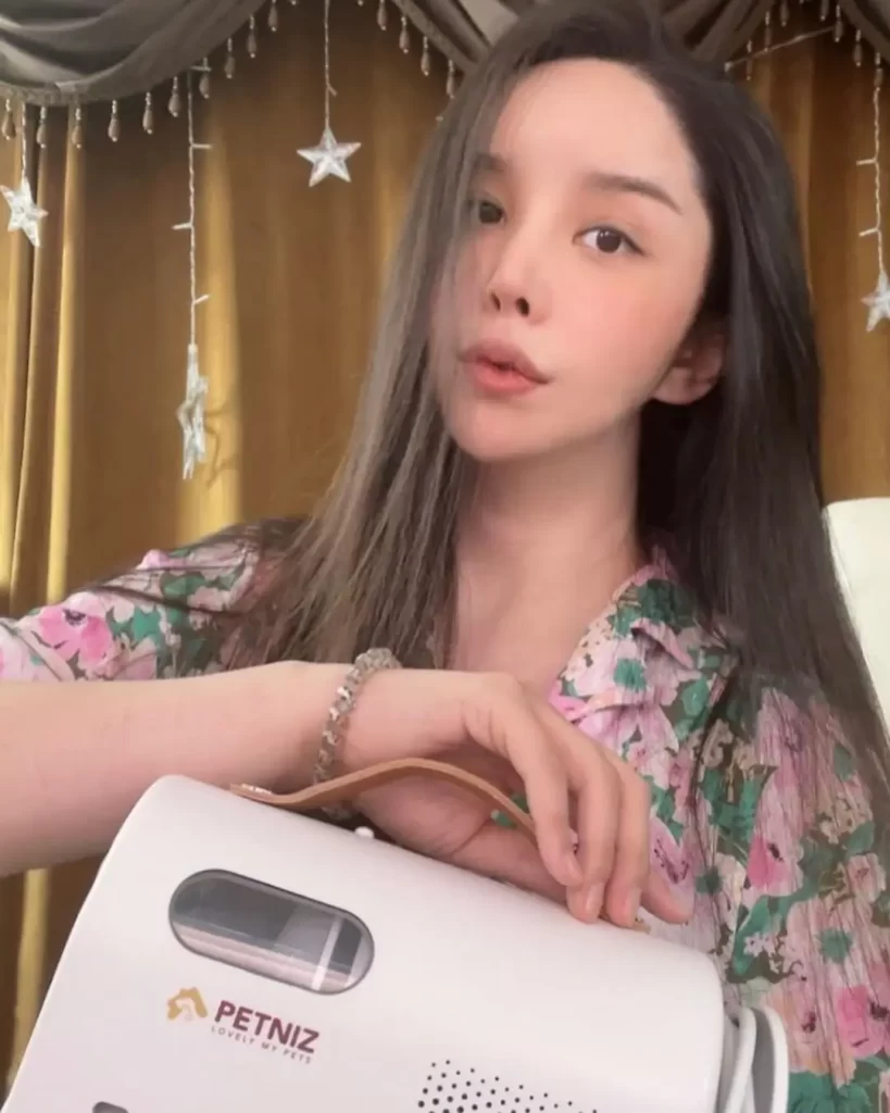 Harisu with floral shirt holding a portable device.