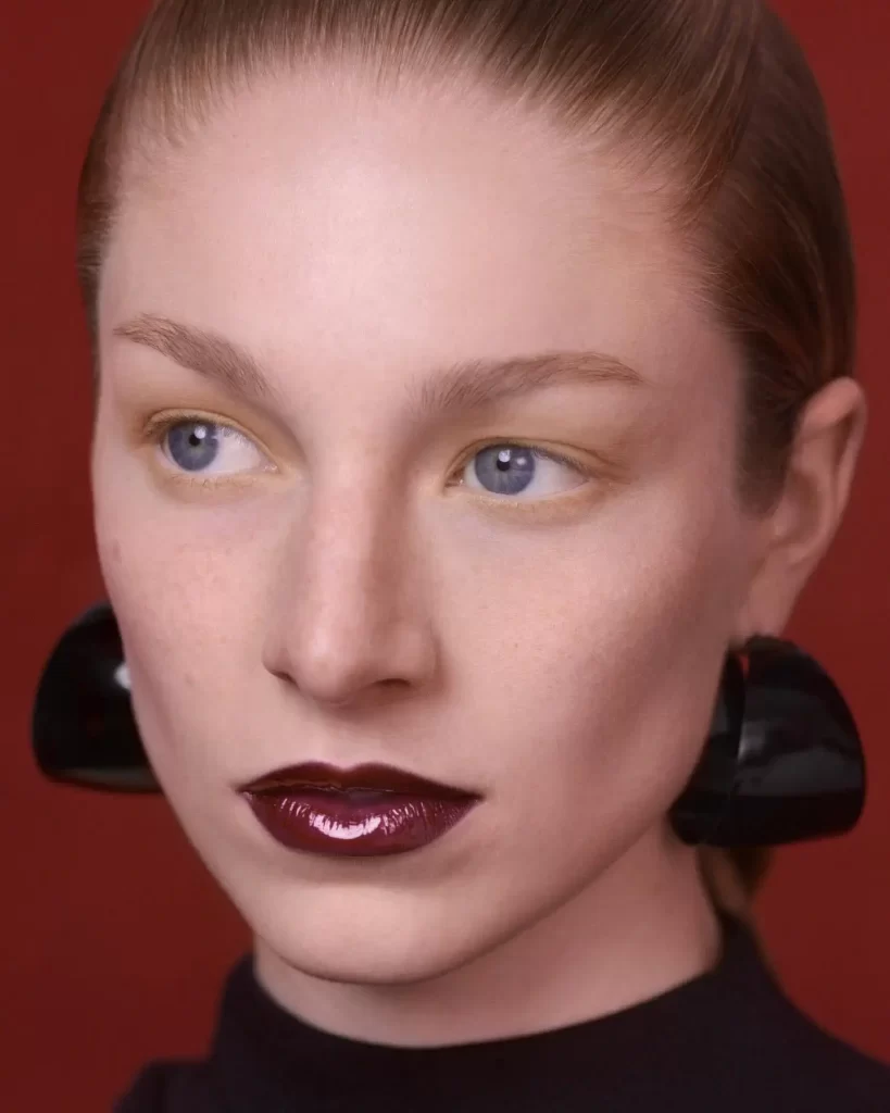 Hunter Schafer with blue eyes and dark lipstick.