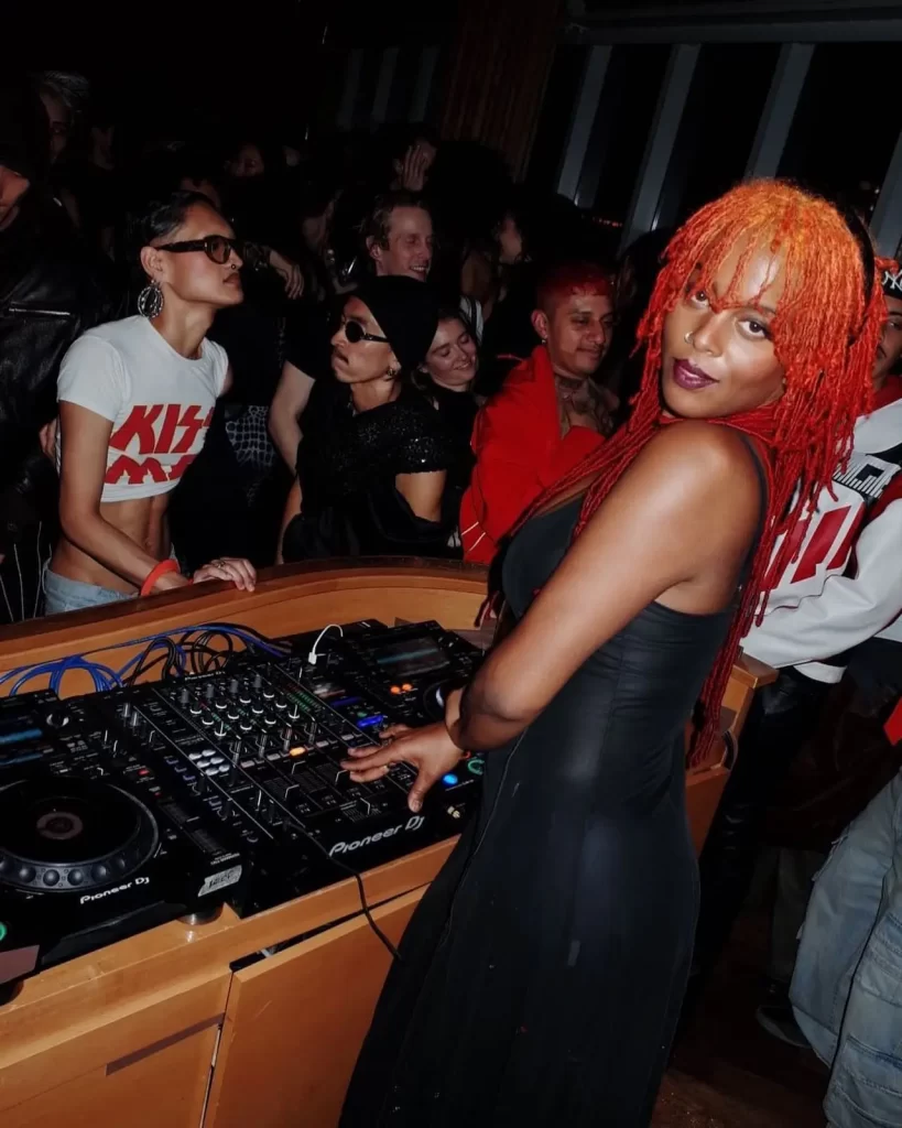 Juliana Huxtable DJ playing music at a lively club party.