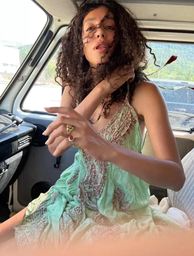Lea T holding flower in vintage car interior.