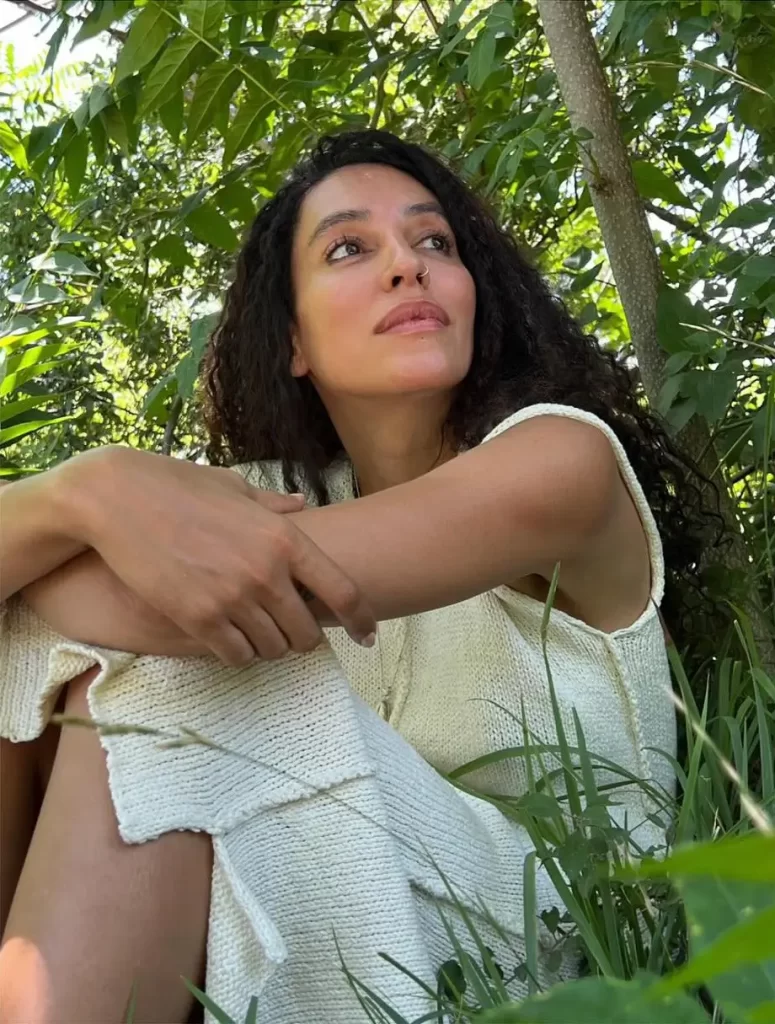 Lea T contemplating in lush greenery.