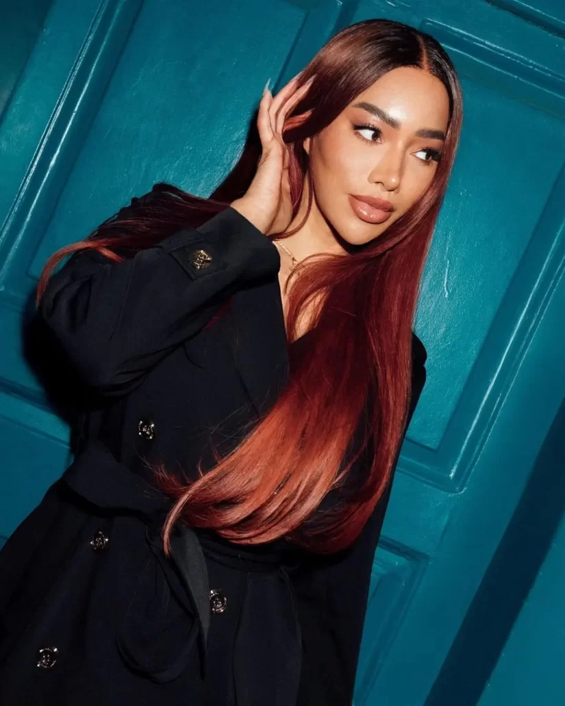 Munroe Bergdorf with red hair posing by blue door.