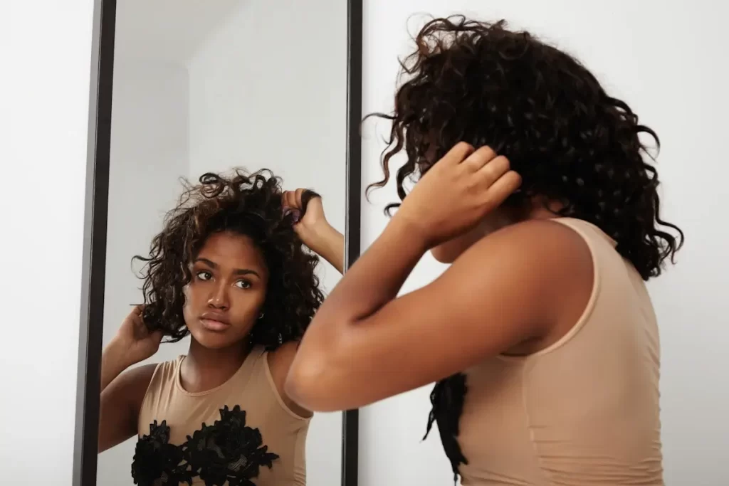 negra-trans-mujer-puesta-peluca-mirando-espejo