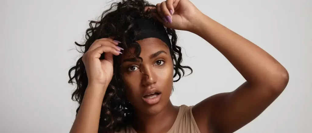 mujer negra transexual sorprendida intentando ponerse peluca rizada