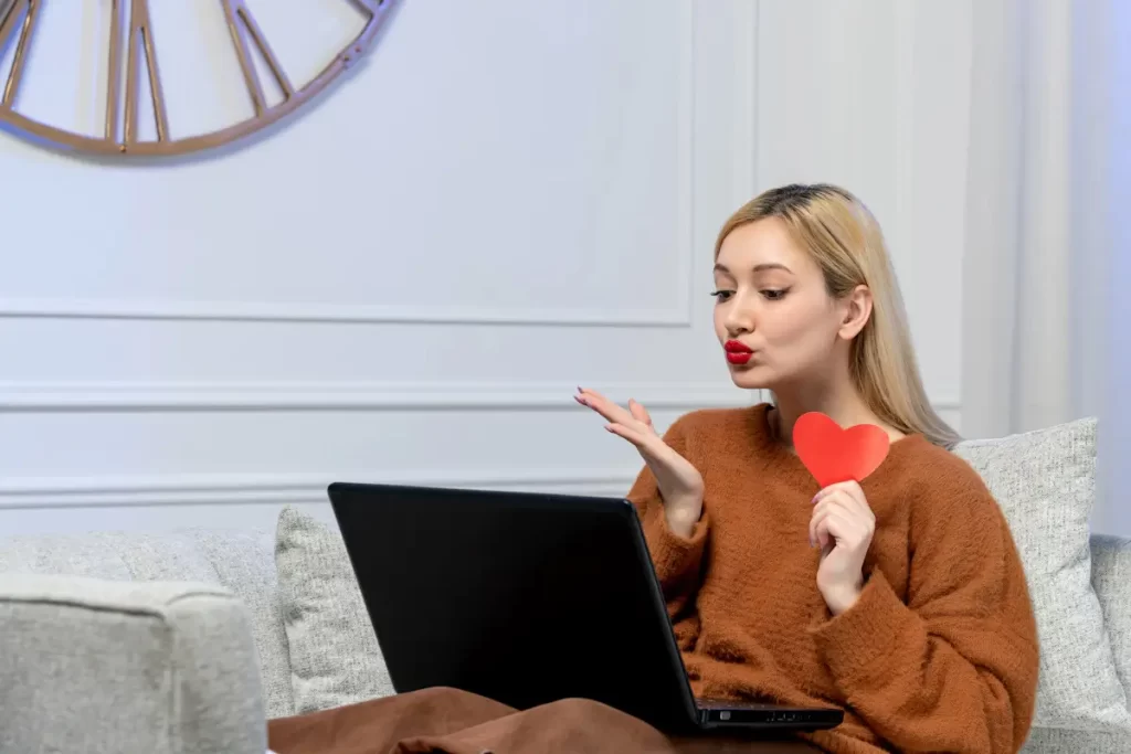 Trans Woman holding heart shape while using laptop