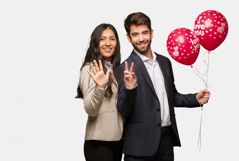 Ein Paar lächelt neben herzförmigen Luftballons